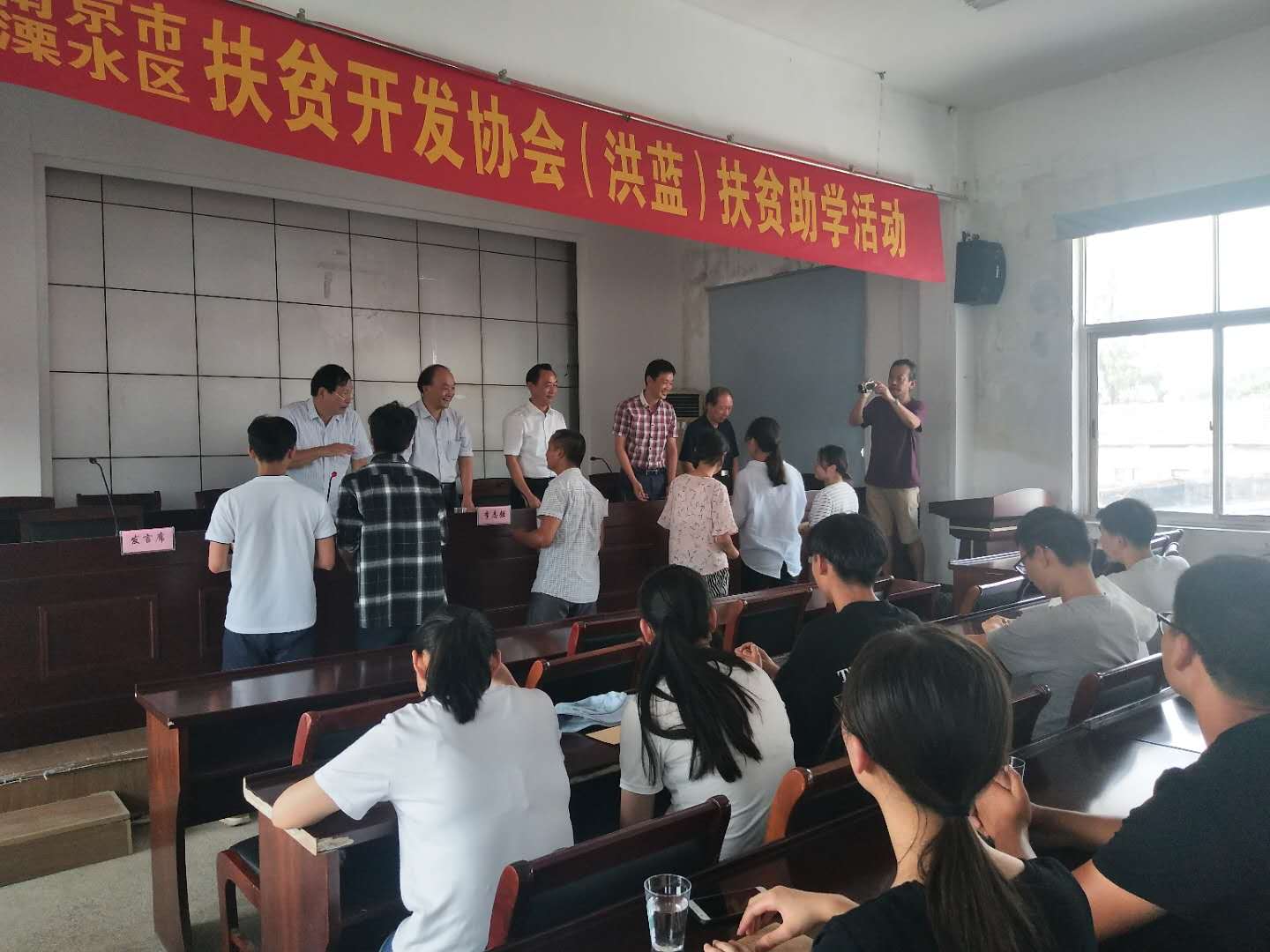 市、区老区扶贫“三会"陪同市驾培协会到洪蓝街道开展扶贫助学活动