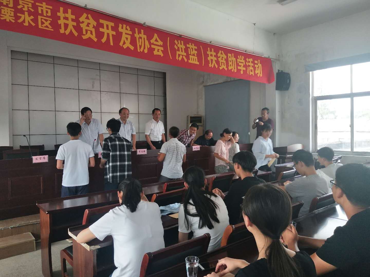 市、区老区扶贫“三会"陪同市驾培协会到洪蓝街道开展扶贫助学活动